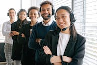 A diverse group of smiling call center agents in an office setting.